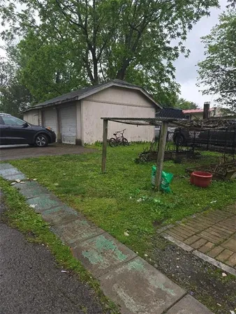 a backyard of a house with plants and large tree