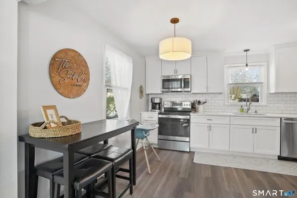 a kitchen with stainless steel appliances granite countertop a stove a sink dishwasher a dining table and chairs with wooden floor