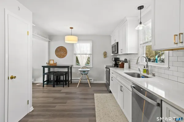 a kitchen with kitchen island granite countertop a stove a sink a dining table and chairs with wooden floor