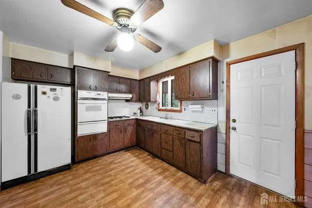 a kitchen with stainless steel appliances granite countertop a refrigerator a sink dishwasher and a stove with wooden floor