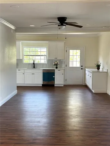 a kitchen with stainless steel appliances a large window a wooden floor and next to a window