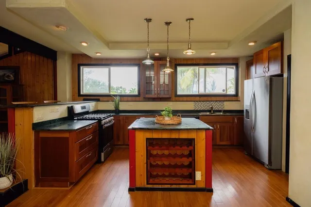 a kitchen with stainless steel appliances granite countertop a refrigerator a stove and a sink