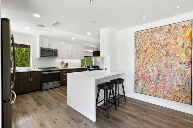 a kitchen with granite countertop a refrigerator stove top oven and sink