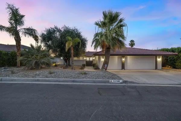 a view of a house with a yard and palm trees