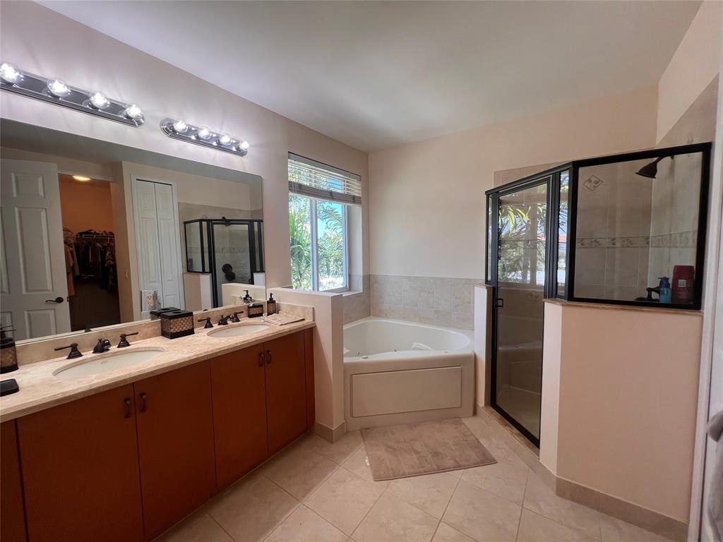 3014 Waterside Circle Boynton Beach, FL 33435 - Photo 17 of 40 a bathroom with a tub a double vanity sink a mirror a window and a shower