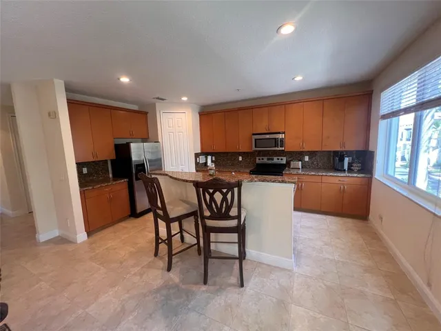 a kitchen with granite countertop a refrigerator and a stove top oven