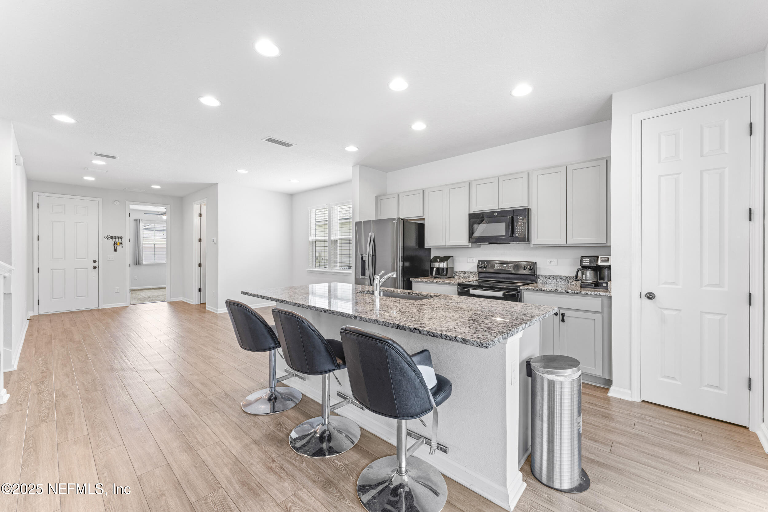 513 Sandstone Drive St. Augustine, FL 32086 - Photo 16 of 56 a kitchen with stainless steel appliances granite countertop a stove a sink a refrigerator and white cabinets with wooden floor