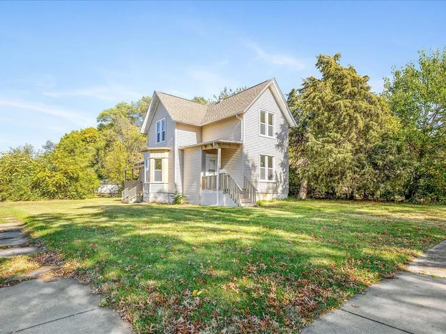 a view of a big house with a big yard and large trees