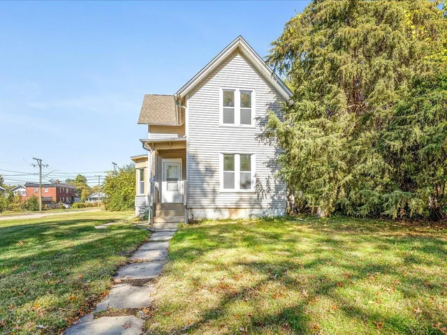 a view of a big house with a big yard and large trees