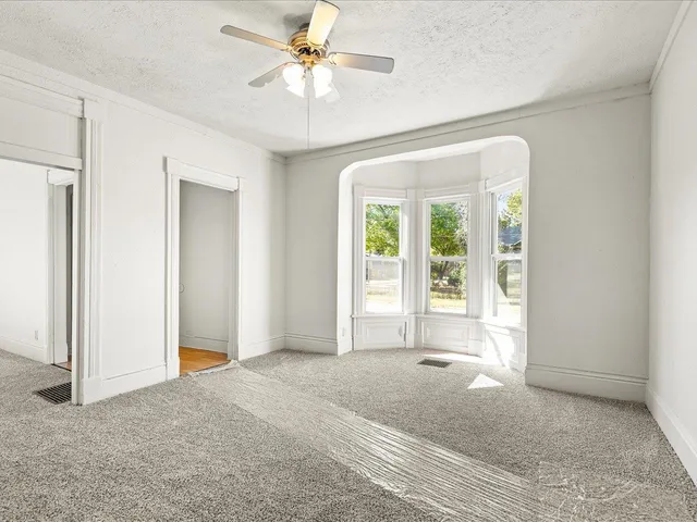 an empty room with fan and windows