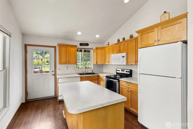 a kitchen with granite countertop a refrigerator a stove top oven a sink and dishwasher with wooden floor