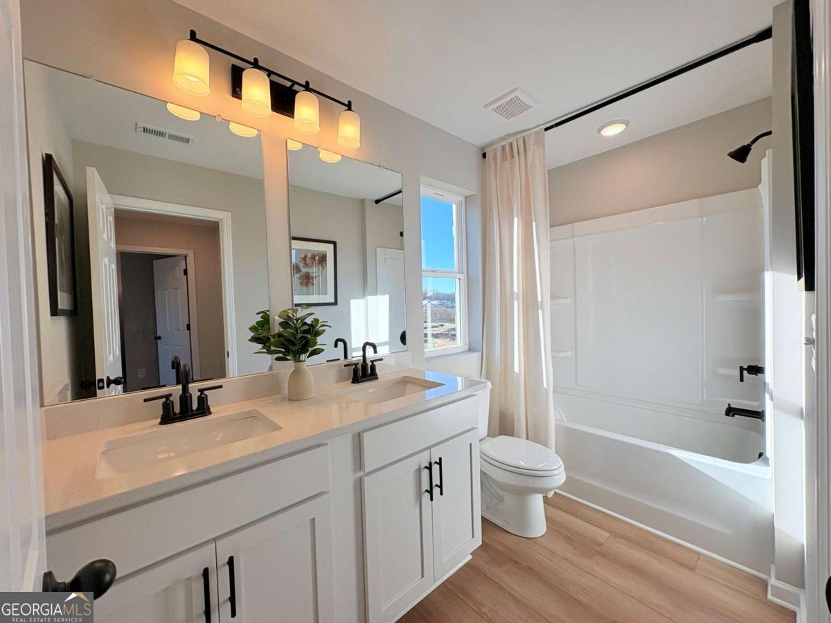 6155 Molo Lane Cumming, GA 30041 - Photo 17 of 29 a bathroom with a double vanity sink toilet mirror and bathtub