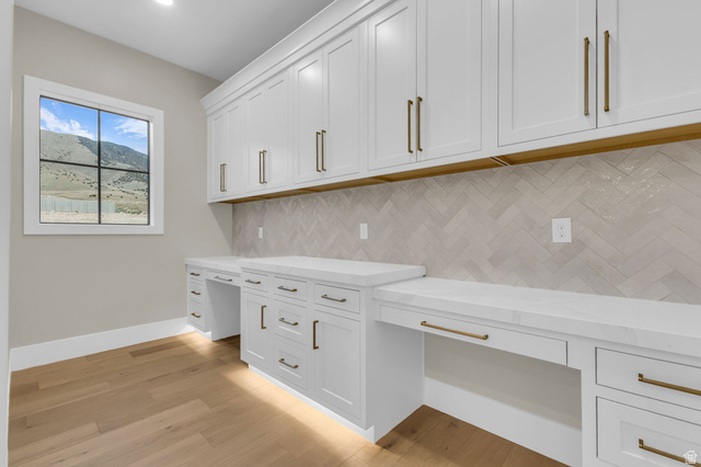 2828 Jojo Road Eagle Mountain, UT 84005 - Photo 22 of 63 Dedicated workspace featuring built-in white shaker cabinetry, white countertops, and a herringbone-patterned tile backsplash