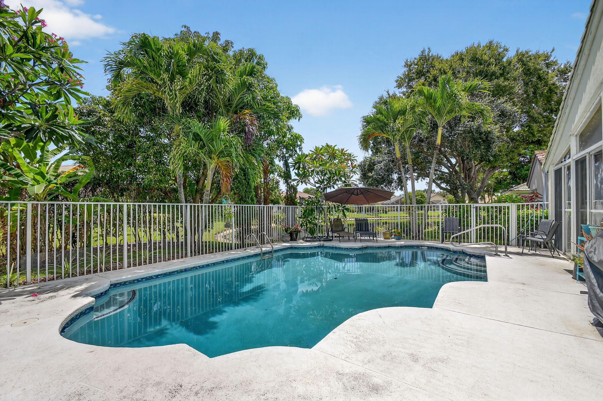2804 Waters Edge Circle Greenacres, FL 33413 - Photo 43 of 74 a view of a swimming pool with a garden and trees