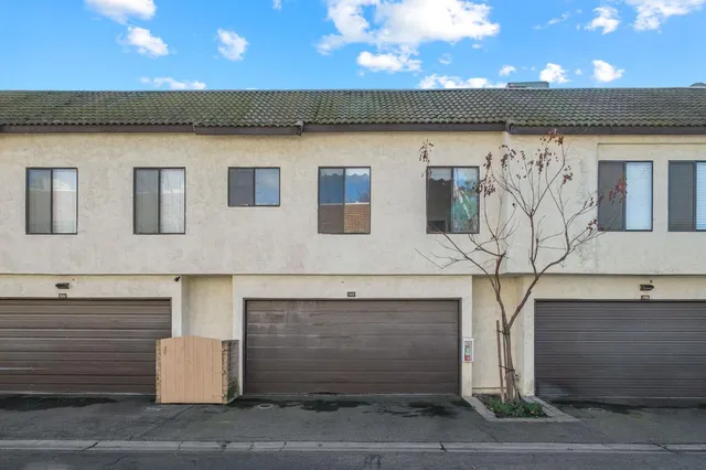 a front view of a building with a garden and garage