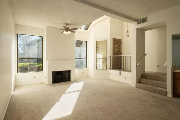 en empty room with windows and fireplace