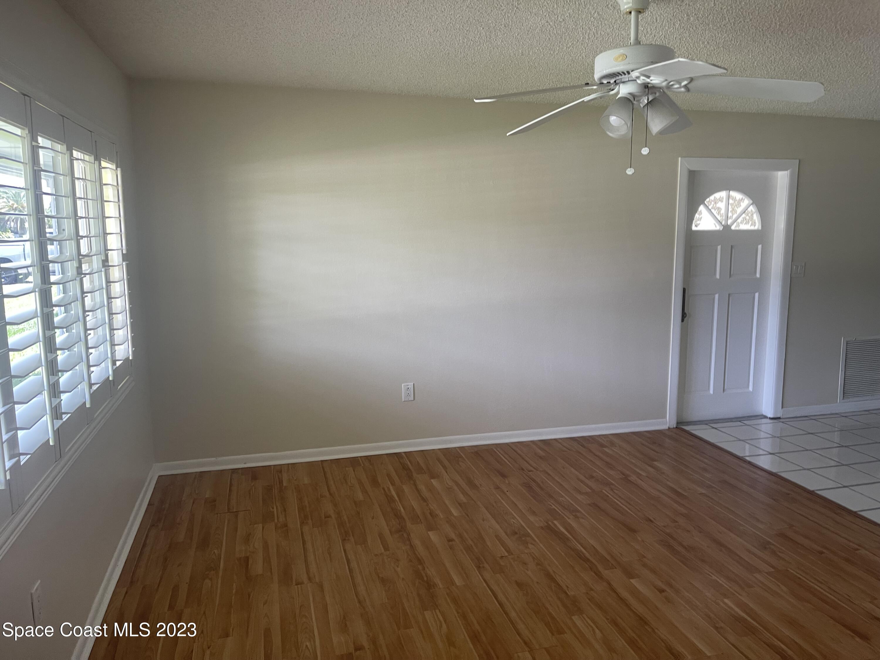 814 Hampton Way Merritt Island, FL 32953 - Photo 3 of 9 an empty room with windows and fan