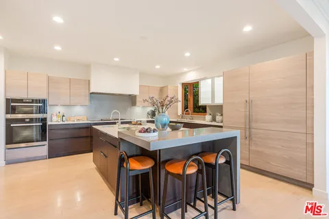 a kitchen with stainless steel appliances granite countertop a sink a stove a refrigerator and island with wooden floor