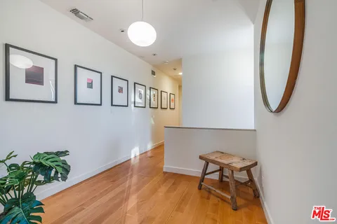 a view of a hallway with wooden floor and a potted plant