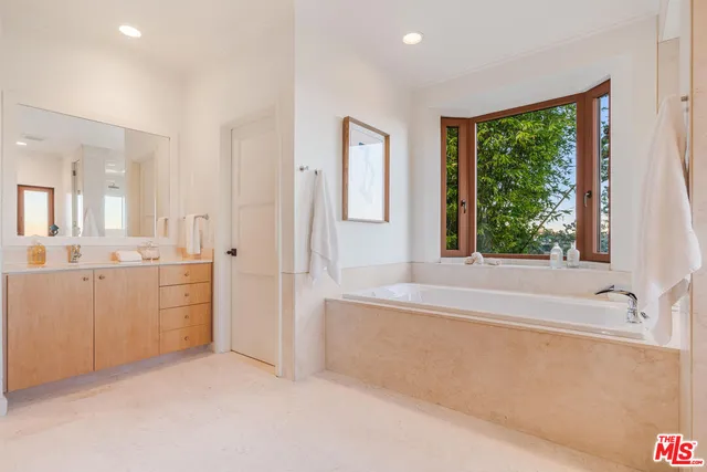 a bathroom with a granite countertop sink mirror bathtub and next to a window
