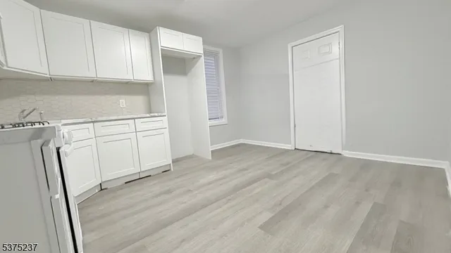 a view of a kitchen with white cabinets and wooden floor