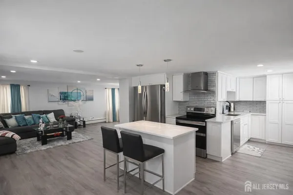 a kitchen with stainless steel appliances a stove a sink a refrigerator white cabinets and wooden floor