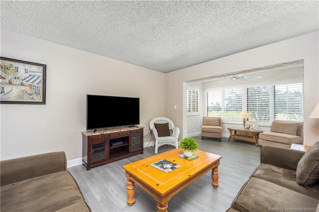 5313 Southeast Miles Grant Road, Unit K209 Stuart, FL 34997 - Photo 10 of 20 a living room with furniture a flat screen tv and a large window