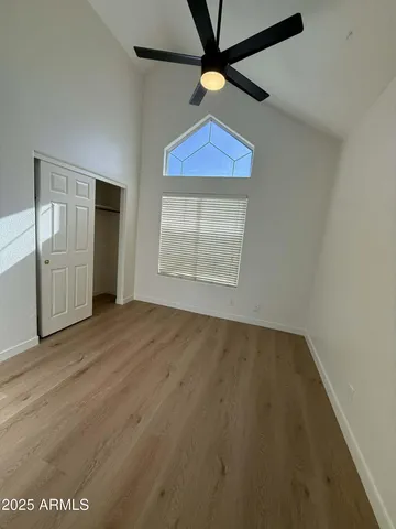 an empty room with wooden floor fan and windows