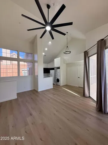 an empty room with wooden floor fan and windows