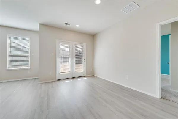 a view of an empty room with wooden floor and windows