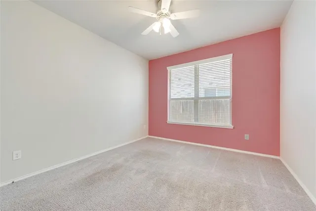 an empty room with a window and ceiling fan
