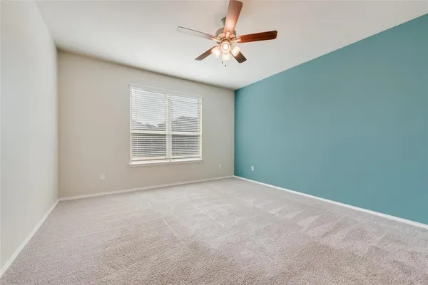 an empty room with windows and ceiling fan