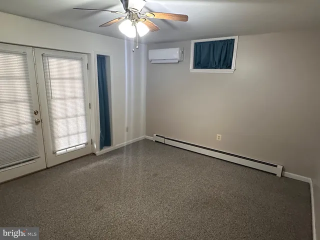 an empty room with windows and chandelier fan