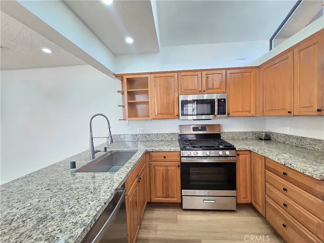 a kitchen with granite countertop a stove sink and microwave