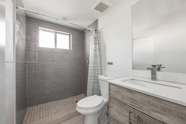 a bathroom with a granite countertop toilet a sink a mirror and shower