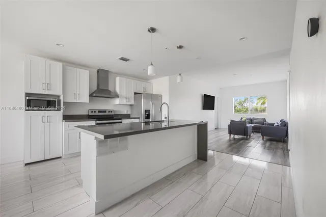 a kitchen with stainless steel appliances a sink a stove a microwave a center island and cabinets