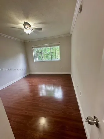 an empty room with wooden floor chandelier fan and windows