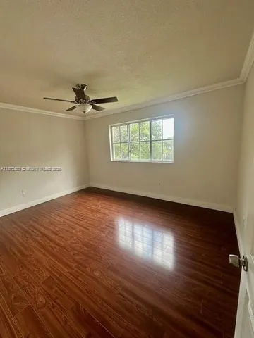an empty room with wooden floor fan and windows