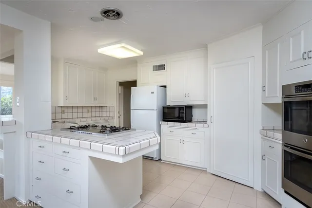 a kitchen with white cabinets and stainless steel appliances