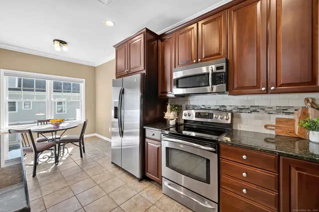 a kitchen with granite countertop wooden cabinets stainless steel appliances and a window