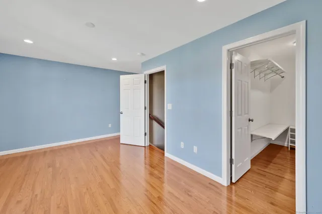 a view of an empty room with wooden floor and a bathroom