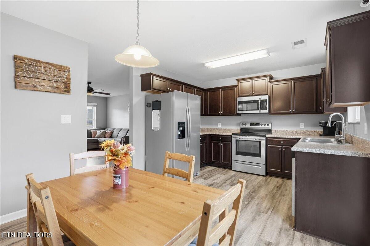 7151 Forest Willow Lane Corryton, TN 37721 - Photo 8 of 24 a kitchen with stainless steel appliances granite countertop a sink a stove a refrigerator with a dining table and chairs