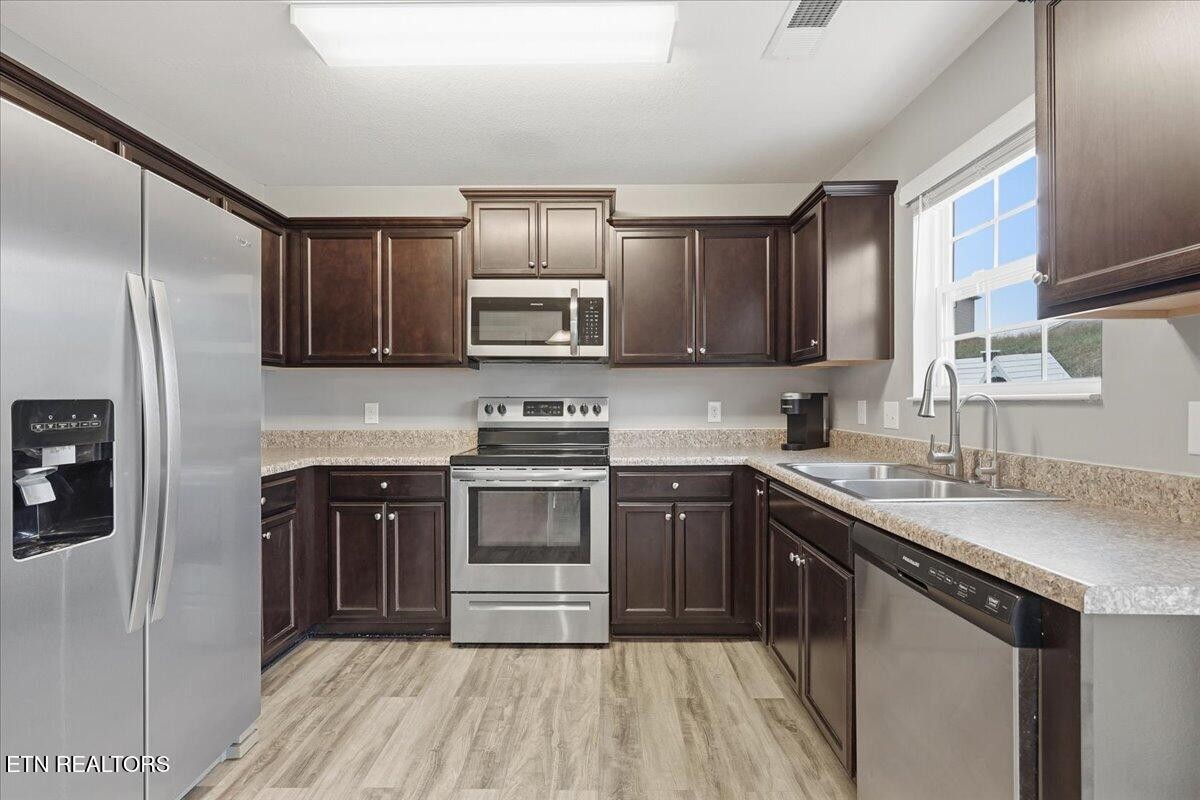 7151 Forest Willow Lane Corryton, TN 37721 - Photo 9 of 24 a kitchen with stainless steel appliances granite countertop a sink stove microwave and refrigerator
