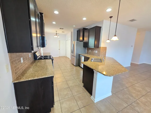 a kitchen with kitchen island granite countertop a sink and a refrigerator