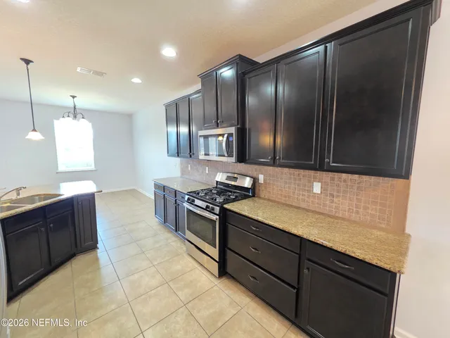 a kitchen with stainless steel appliances granite countertop wooden cabinets a stove top oven and sink