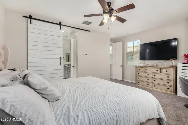 a bedroom with a bed a flat screen tv and a chandelier