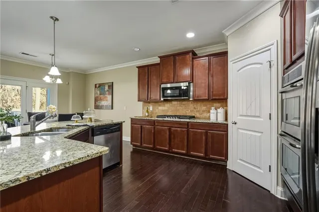 a large kitchen with granite countertop a large counter top appliances and cabinets