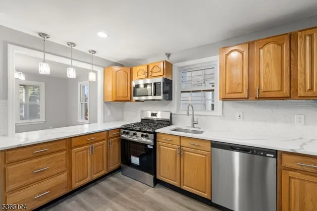 a kitchen with stainless steel appliances granite countertop wooden cabinets and a stove top oven