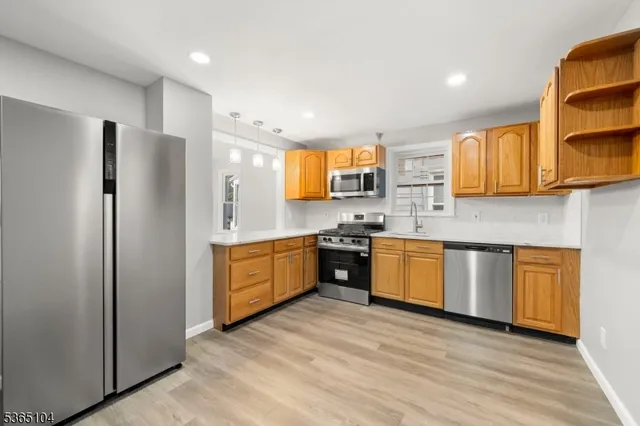 a kitchen with stainless steel appliances granite countertop a refrigerator a sink dishwasher a oven with wooden cabinets and floor