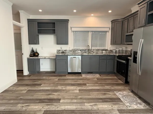 a kitchen with stainless steel appliances granite countertop a stove top oven a refrigerator and a sink
